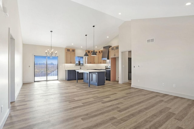 kitchen featuring pendant lighting, a breakfast bar, a center island, tasteful backsplash, and wall chimney exhaust hood