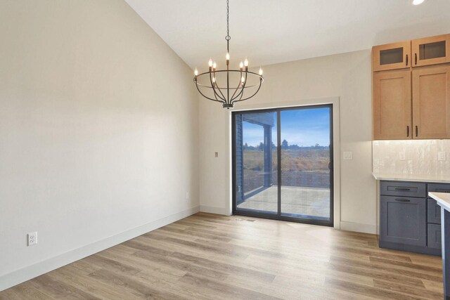 unfurnished dining area with a chandelier and light wood-type flooring