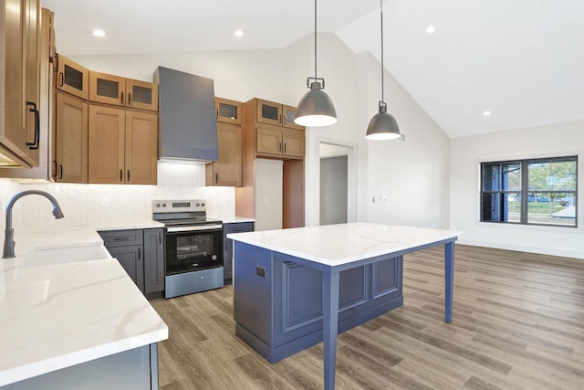 kitchen with electric stove, pendant lighting, a large island, light stone countertops, and wall chimney exhaust hood