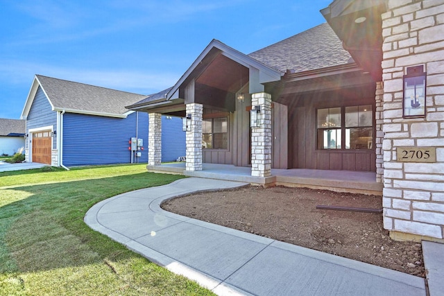 view of exterior entry with a garage, a yard, and covered porch