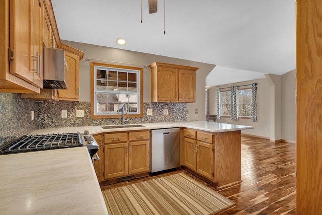 kitchen featuring sink, stainless steel appliances, light hardwood / wood-style floors, decorative backsplash, and kitchen peninsula