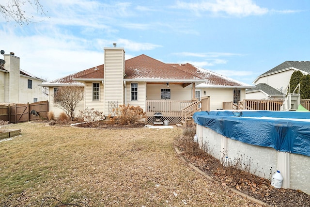 rear view of property with a swimming pool side deck and a yard