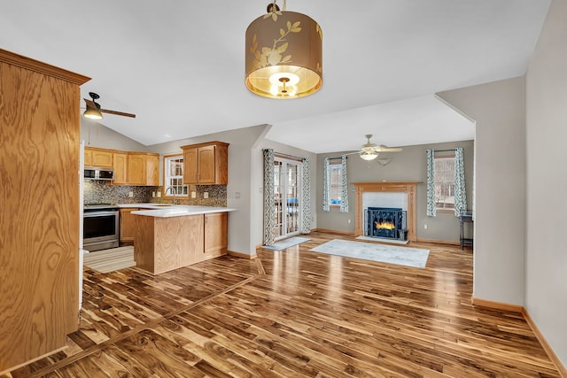 kitchen featuring lofted ceiling, kitchen peninsula, hardwood / wood-style flooring, ceiling fan, and stainless steel electric stove