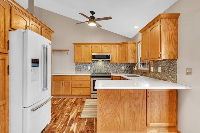 kitchen with sink, light hardwood / wood-style flooring, stainless steel appliances, vaulted ceiling, and kitchen peninsula