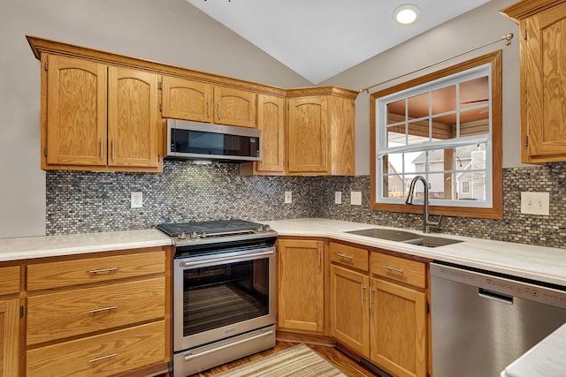 kitchen featuring appliances with stainless steel finishes, sink, lofted ceiling, and decorative backsplash