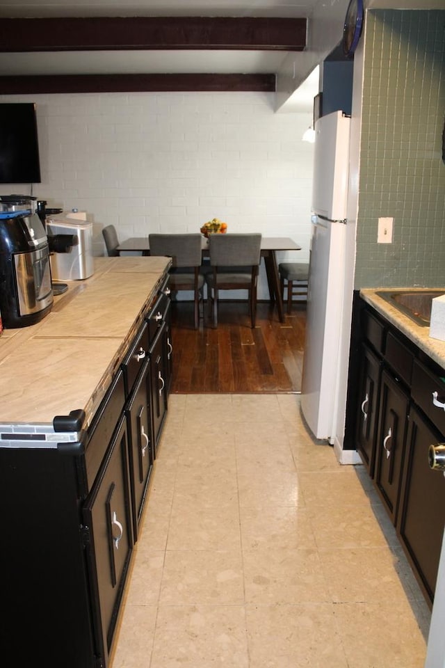 kitchen featuring sink, beam ceiling, and white fridge