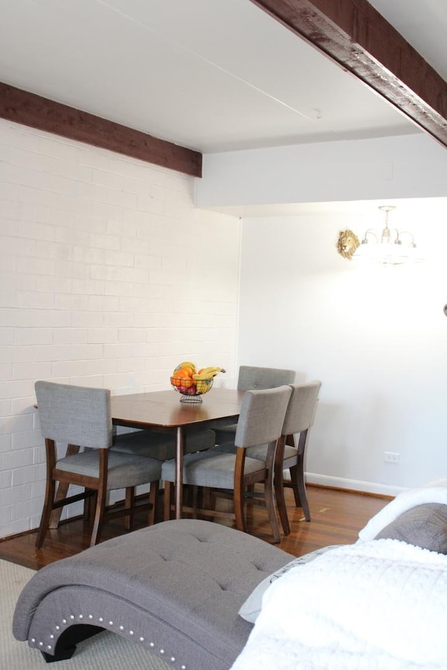 dining space featuring brick wall and dark wood-type flooring