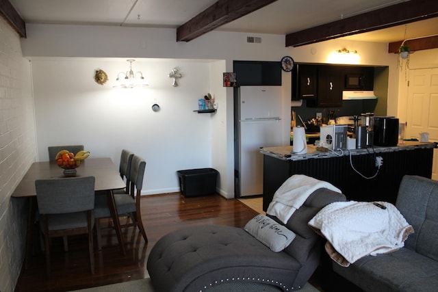 kitchen with beam ceiling, brick wall, a kitchen bar, kitchen peninsula, and white fridge