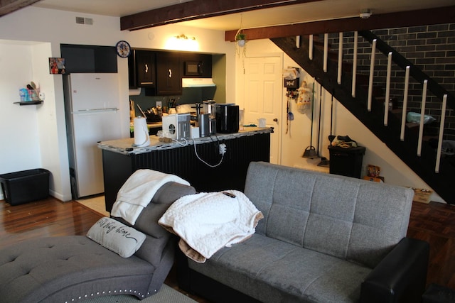 kitchen featuring beam ceiling, hardwood / wood-style floors, and white fridge