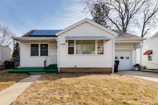 view of front of home featuring a garage, a front lawn, and solar panels