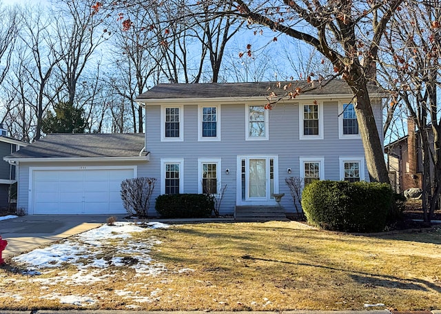 colonial-style house featuring a garage and a front yard