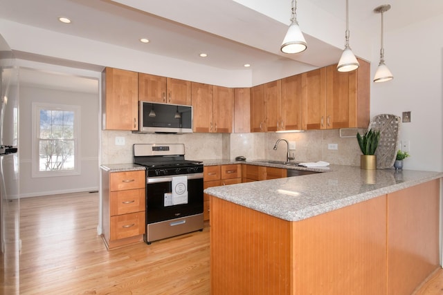 kitchen with sink, tasteful backsplash, light hardwood / wood-style flooring, kitchen peninsula, and stainless steel appliances