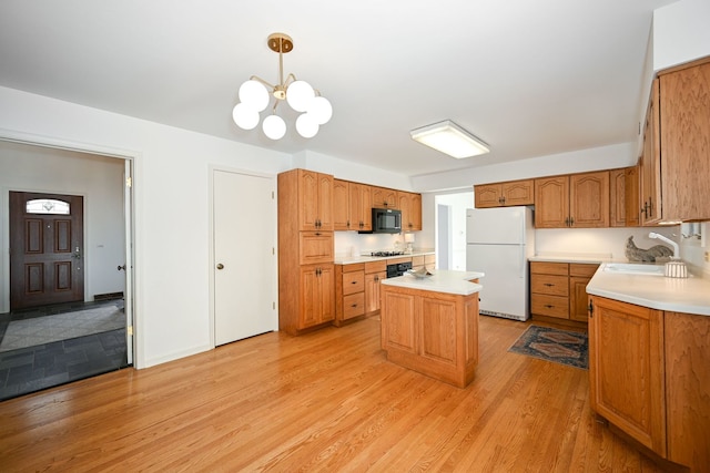 kitchen featuring sink, a center island, light hardwood / wood-style floors, decorative light fixtures, and white fridge