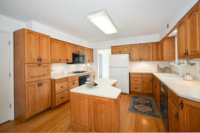 kitchen with sink, black appliances, a center island, and light wood-type flooring