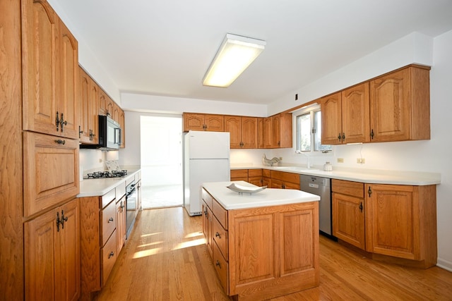 kitchen with white fridge, a center island, stainless steel dishwasher, and light wood-type flooring