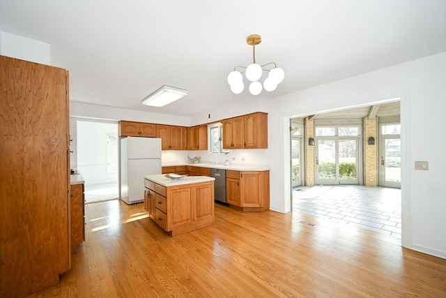 kitchen featuring a center island, hanging light fixtures, white refrigerator, dishwasher, and light hardwood / wood-style floors