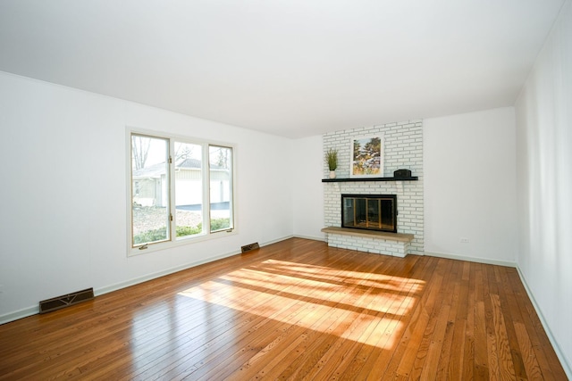 unfurnished living room with a brick fireplace and hardwood / wood-style floors