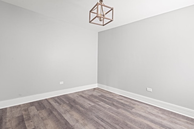 empty room with hardwood / wood-style flooring and a chandelier