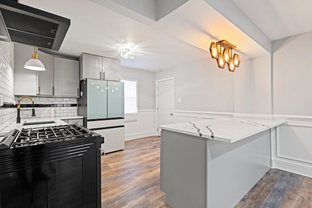 kitchen featuring gray cabinets, pendant lighting, white fridge, gas range, and dark wood-type flooring