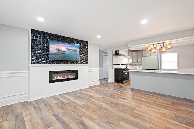 unfurnished living room with sink and light hardwood / wood-style floors