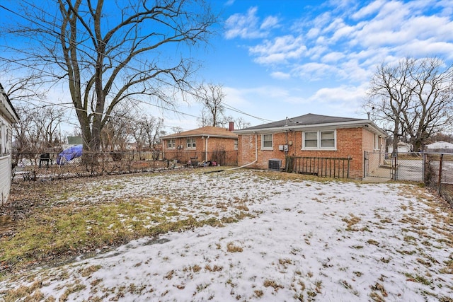 snow covered rear of property featuring central AC unit