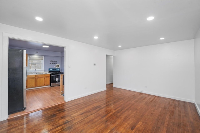 unfurnished living room featuring wood-type flooring and sink