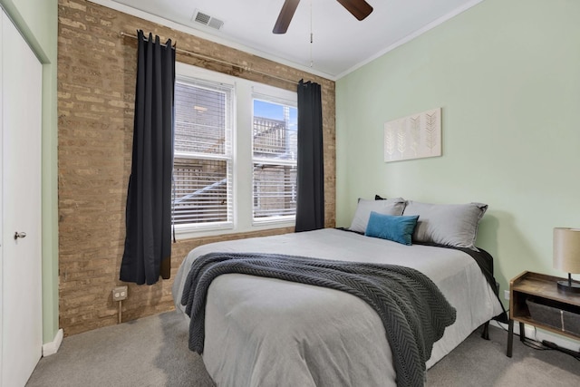 carpeted bedroom with ceiling fan, brick wall, and ornamental molding