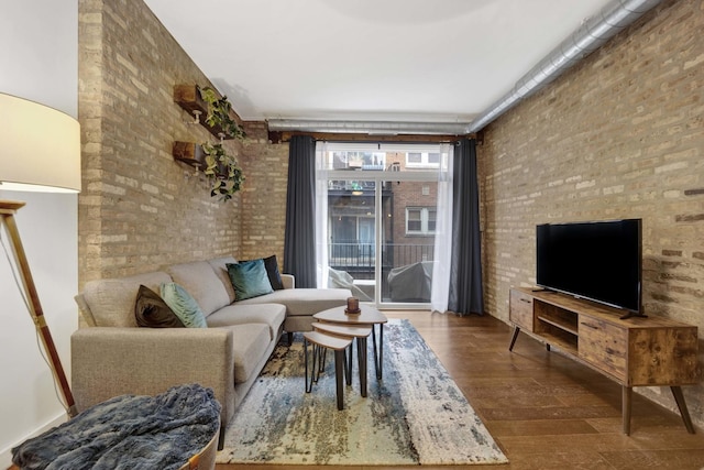 living room featuring hardwood / wood-style flooring, brick wall, and a high ceiling