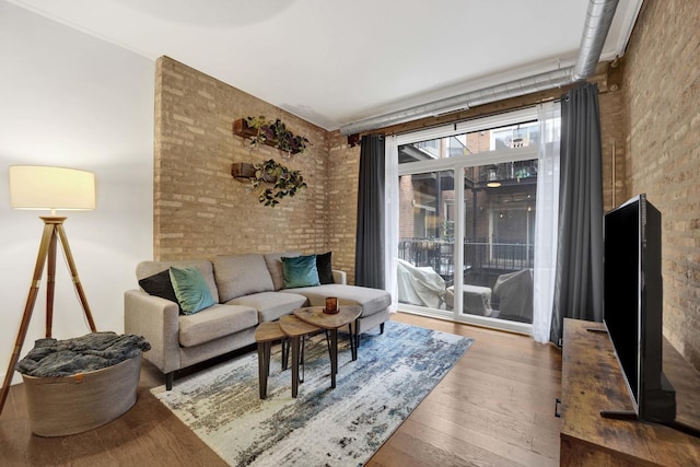 living room featuring wood-type flooring and brick wall