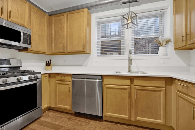 kitchen featuring pendant lighting, light brown cabinetry, sink, light hardwood / wood-style floors, and stainless steel appliances