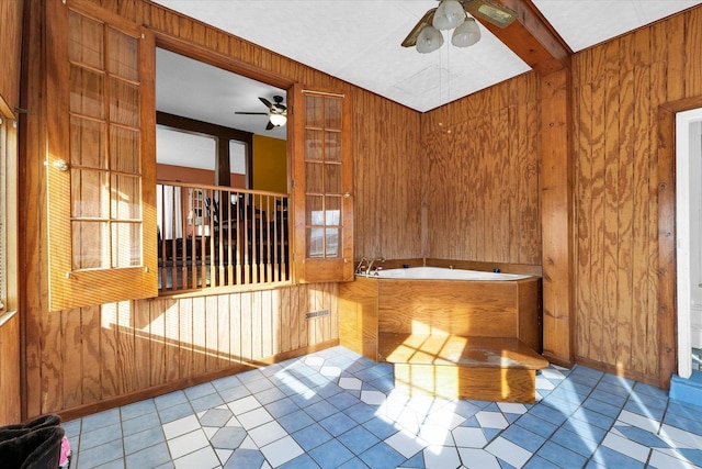 bathroom with ceiling fan, a healthy amount of sunlight, a bathtub, and wood walls