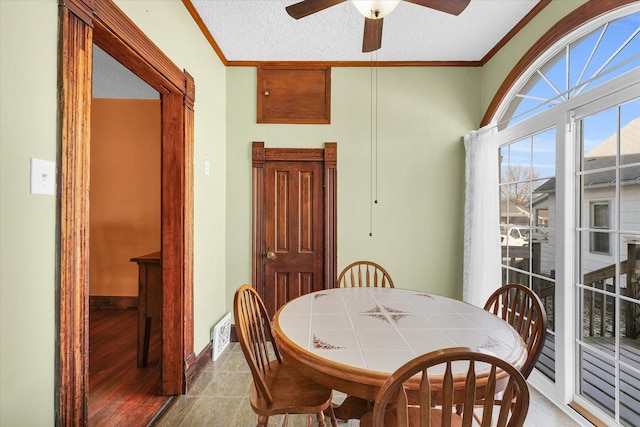 dining room featuring ceiling fan, crown molding, a textured ceiling, and light wood-type flooring