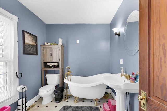 bathroom with a wealth of natural light, a bathtub, and toilet