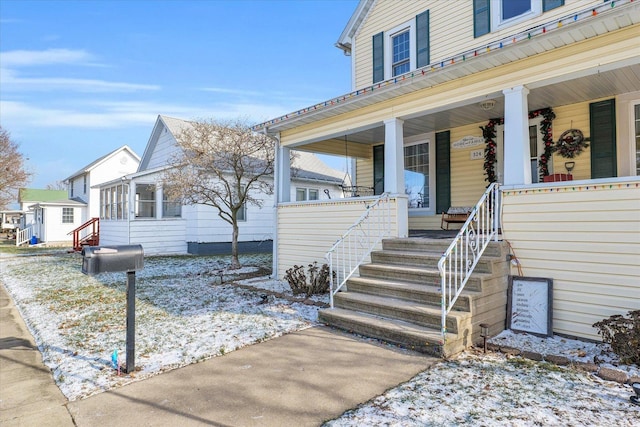 snow covered property entrance featuring a porch