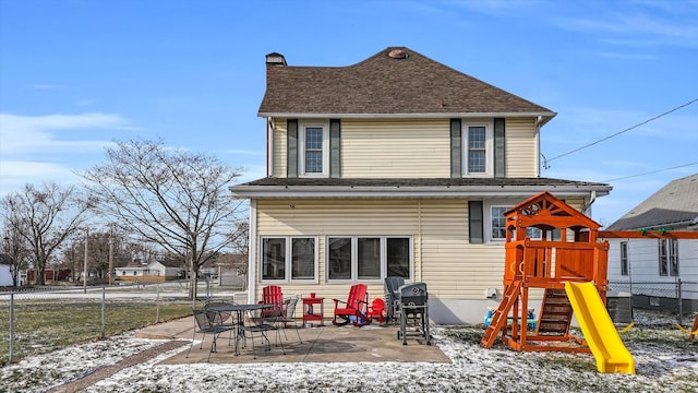 snow covered back of property with cooling unit, a playground, and a patio