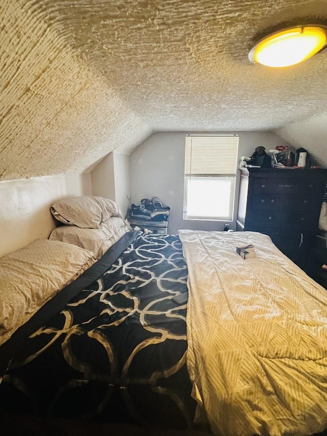 bedroom featuring vaulted ceiling and a textured ceiling