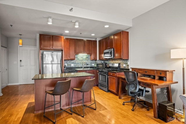 kitchen featuring a kitchen bar, decorative backsplash, light hardwood / wood-style flooring, and appliances with stainless steel finishes