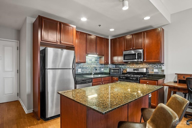 kitchen featuring decorative backsplash, stainless steel appliances, sink, and a kitchen island