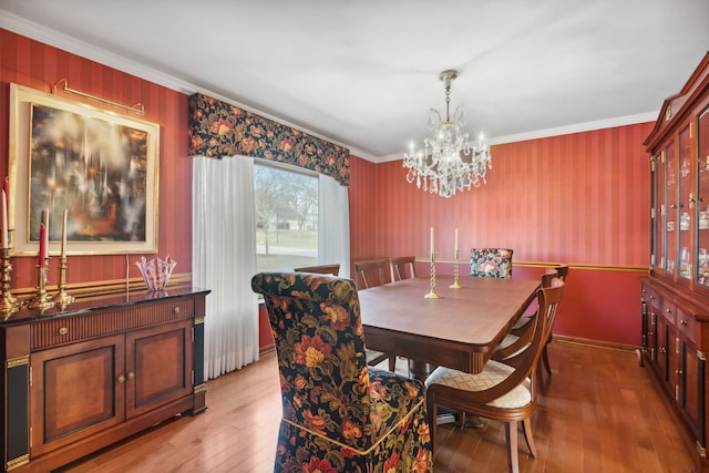 dining space with ornamental molding, light hardwood / wood-style flooring, and a notable chandelier