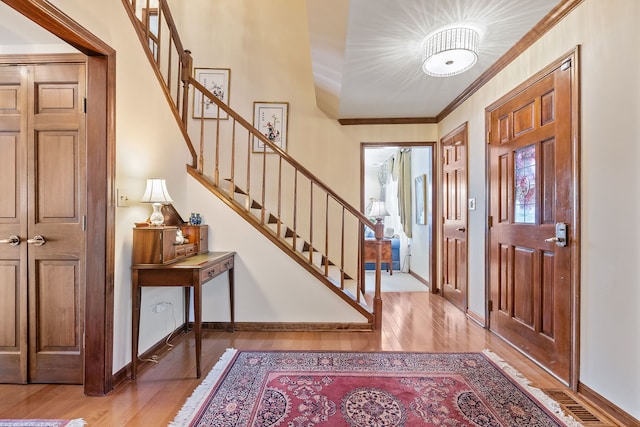 foyer with crown molding and light hardwood / wood-style flooring