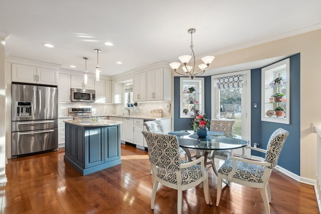 kitchen featuring stainless steel appliances, a center island, white cabinets, and decorative light fixtures