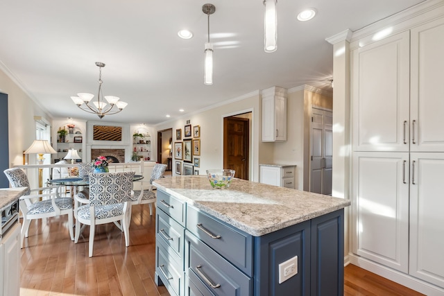 kitchen featuring white cabinetry, hanging light fixtures, ornamental molding, light hardwood / wood-style floors, and blue cabinetry