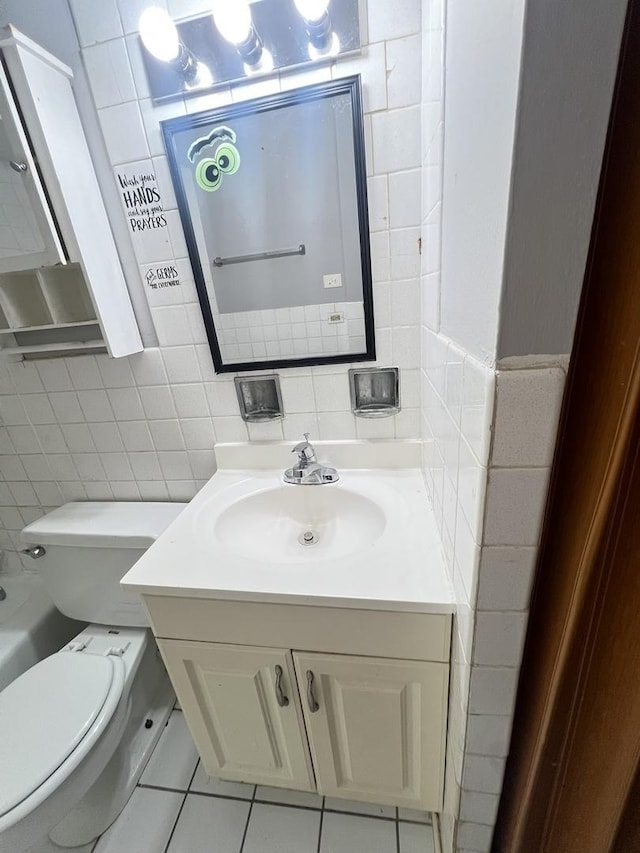 bathroom with tile walls, vanity, tile patterned floors, and toilet