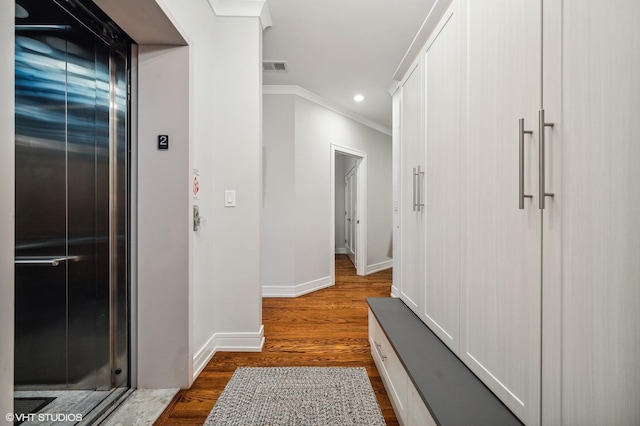 hallway featuring dark wood-type flooring, ornamental molding, and elevator