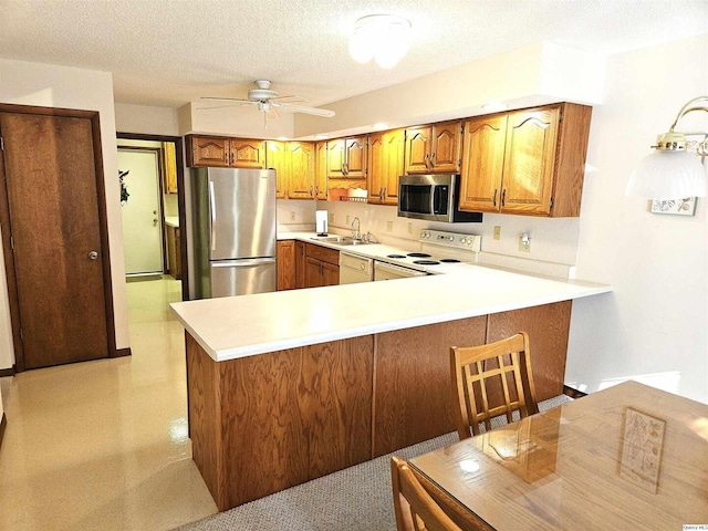 kitchen featuring appliances with stainless steel finishes, sink, ceiling fan, kitchen peninsula, and a textured ceiling