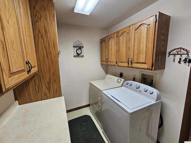 laundry area with cabinets, washer and dryer, and a textured ceiling