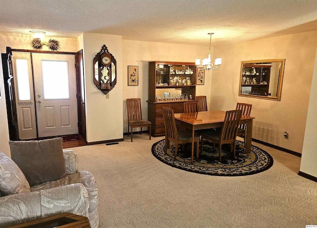 dining area with a notable chandelier, carpet, and a textured ceiling