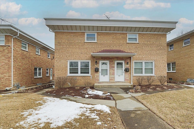 view of front facade with brick siding and a yard