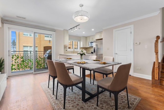 dining area featuring crown molding, track lighting, and light wood-type flooring