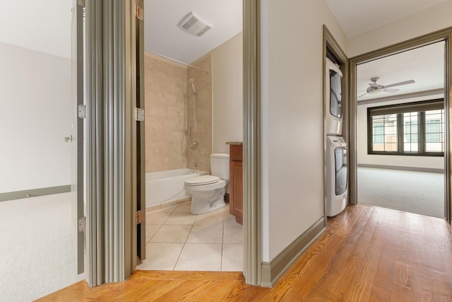 corridor with light hardwood / wood-style floors and stacked washing maching and dryer